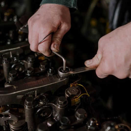 Gros plan d’un technicien travaillant sur un moteur diesel, illustrant le savoir-faire de l’Atelier d’Usinage Moteur de Beauce.