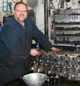 Robert Boutin dans son atelier, illustrant l’expertise locale et le travail minutieux sur un moteur.